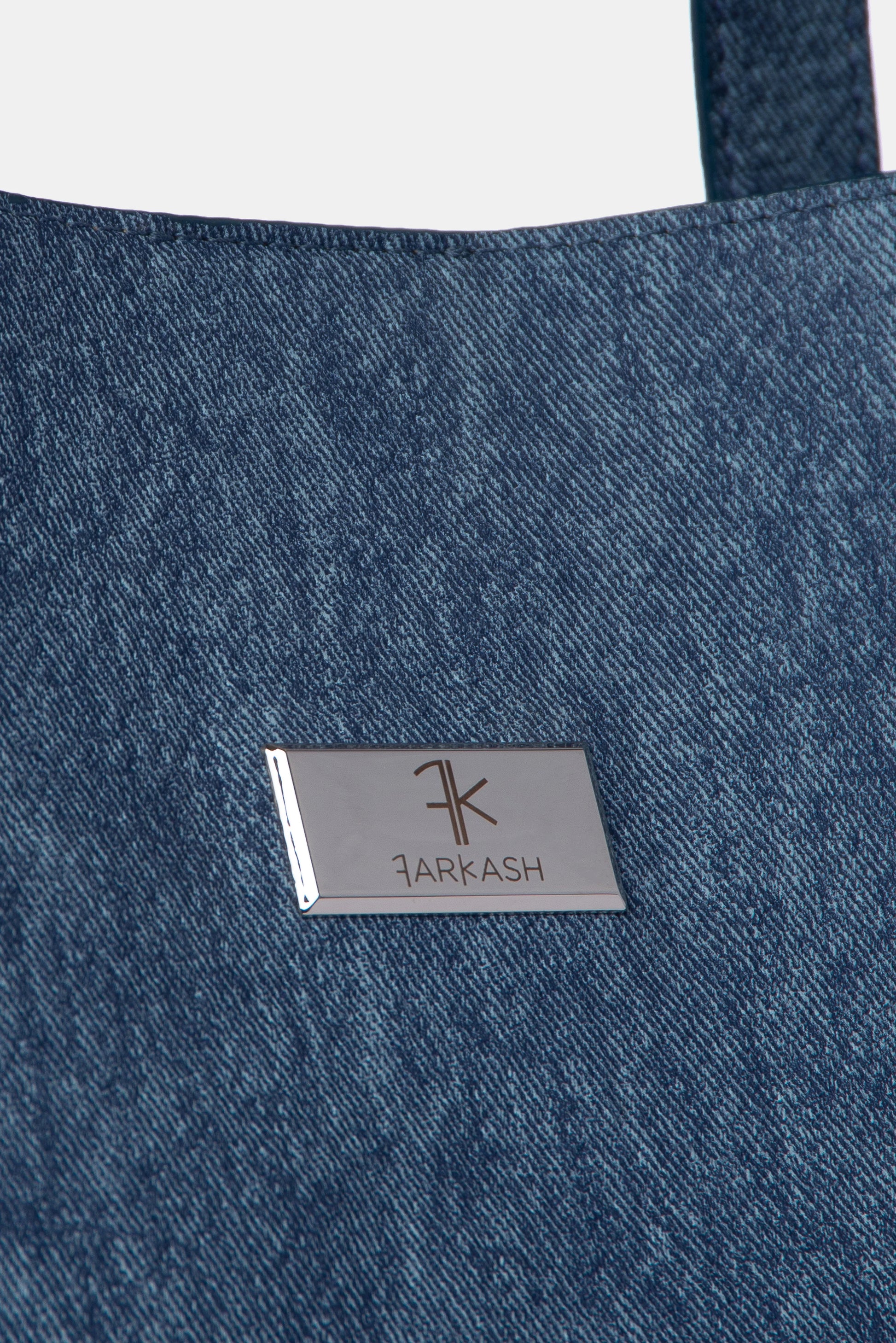 Detalle de bolso de denim azul con logo FARKASH 