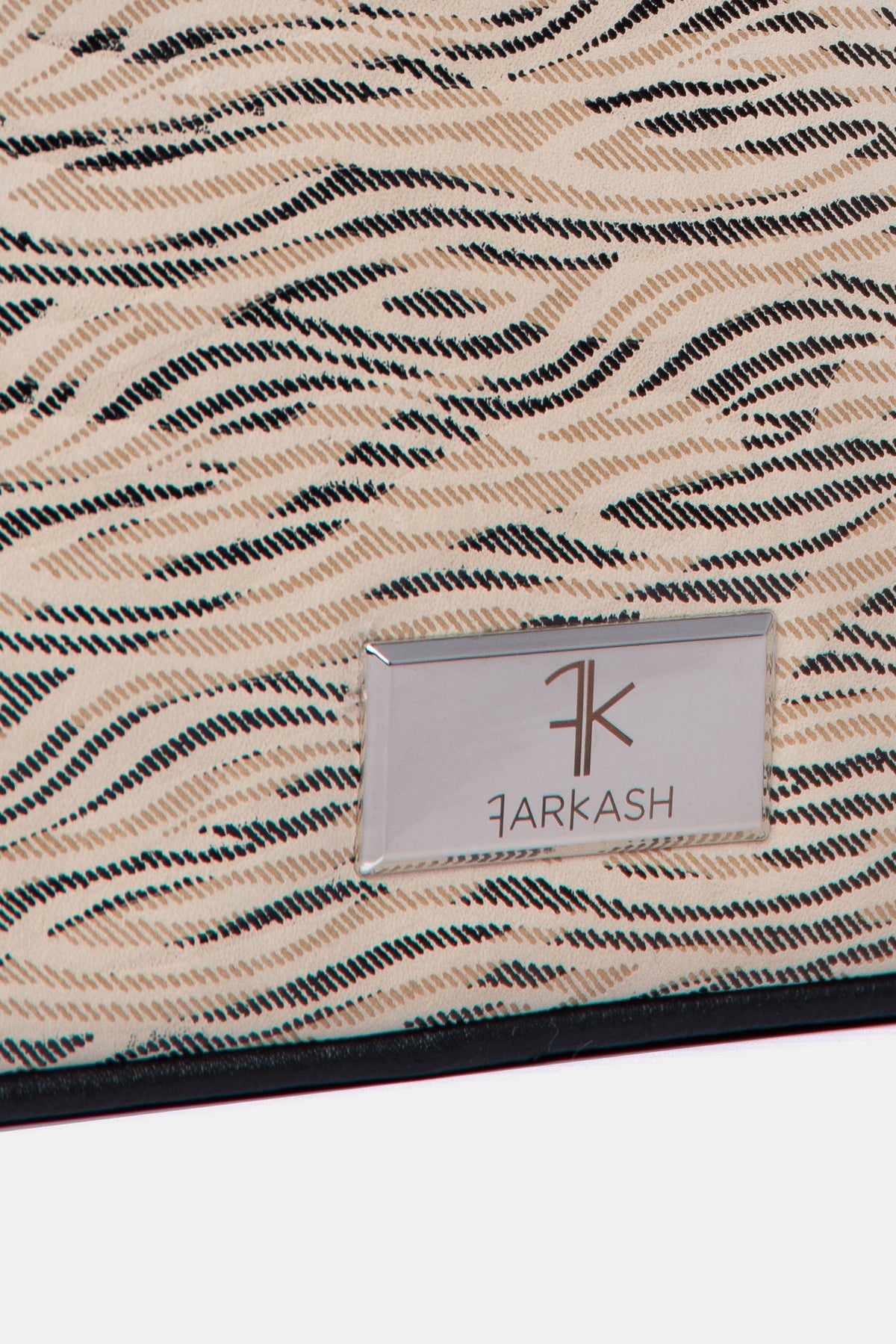Detalle de placa logo FARKASH en el bolso crossbody animal print 